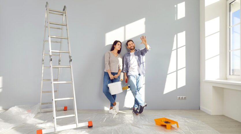 Una pareja con planos en la mano y una escalera cerca porque quieren reformar su casa